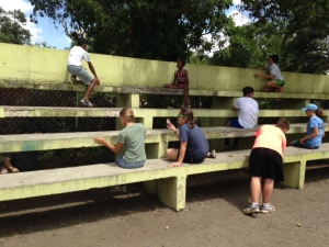 Participants in our mission trip and children from the community work together to scrape and paint bleachers in Santiago.